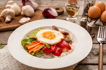Plate with tasty egg, vegetables and rice on wooden background