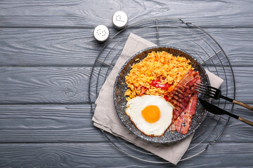 Plate with tasty egg, bacon and rice on wooden background
