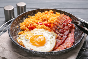 Plate with tasty egg, bacon and rice on wooden background