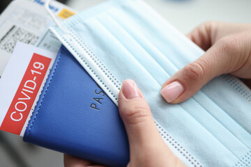 Female hand holding covid-19 vaccination passport and plane tickets closeup. Traveling abroad...