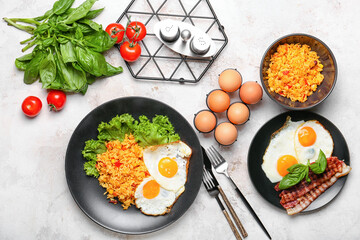 Plates with tasty eggs, bacon and rice on light background