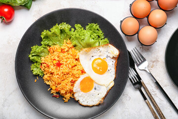 Plate with tasty eggs and rice on light background