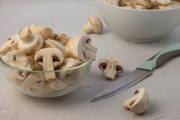 Knife and sliced fresh mushrooms in round bowls