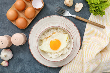 Bowl with tasty egg and rice on dark background