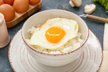 Bowl with tasty egg and rice on dark background