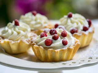 Tart with cream and wild strawberries on porcelain cake stand