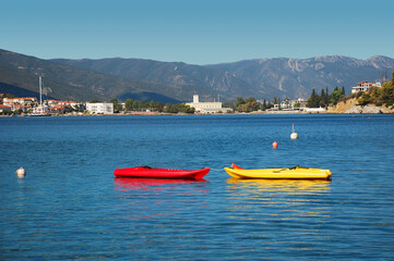 Fototapeta na wymiar Red in yellow boats in a bay of picturesque Greek island called Poros in a sunny summer day.