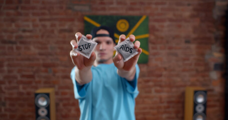 Young caucasian man holding condoms with stop aids inscription on wrap