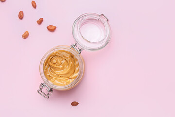 Jar of tasty peanut butter on color background