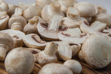Fresh whole and sliced champignons on a dark board close-up. Selective focus