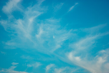 Bright blue sky with moon and clouds