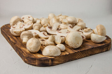 Fresh whole and sliced mushrooms on a burnt cutting board