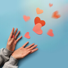 A lot of red and pink hearts fly out of women's hands. Valentine's Day Greeting Card