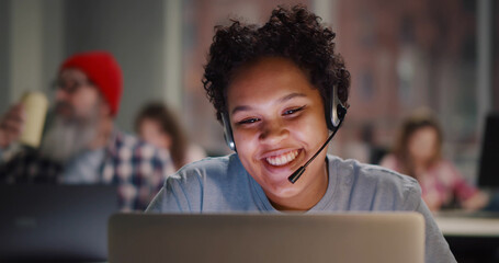 Call center agent with headset working on support hotline in modern office - obrazy, fototapety, plakaty