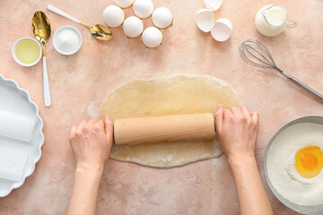 Woman rolling out dough on color background