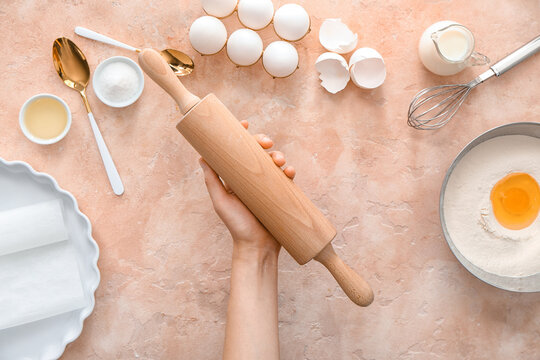 Female hand with rolling pin on color background