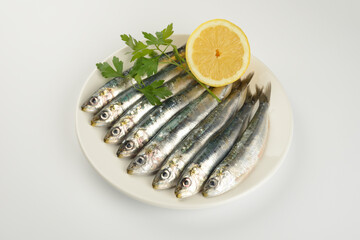 Sardinas crudas en un plato sobre fondo blanco