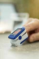 Person using fingertip oximeter at home to measure body oxygen
