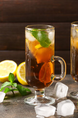 Cup of cold black tea with lemon on wooden background