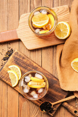 Glasses of cold black tea with lemon on wooden background