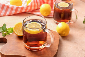 Cups of cold black tea with lemon on color background