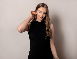 Fototapeta premium Beautiful young woman with long shiny and healthy hair posing in dress on grey background