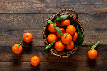 Fototapeta na wymiar Tangerines, fresh mandarin oranges, clementines with leaves on wooden background. Top view, copy space