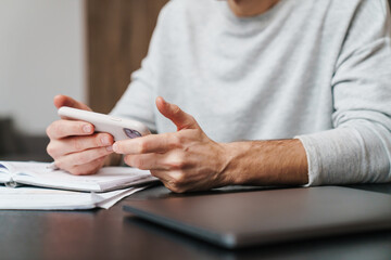 Focused handsome man using mobile phone while working at home