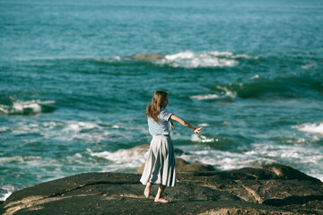 A woman is engaged in choreography on the ocean coast.