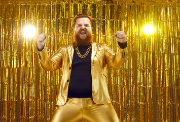 Happy crazy funky uninhibited ginger young man wearing funny golden suit and extravagant gold chain...