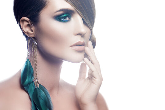 Model in stylish image with sleek hair covering one eye and feather earring
