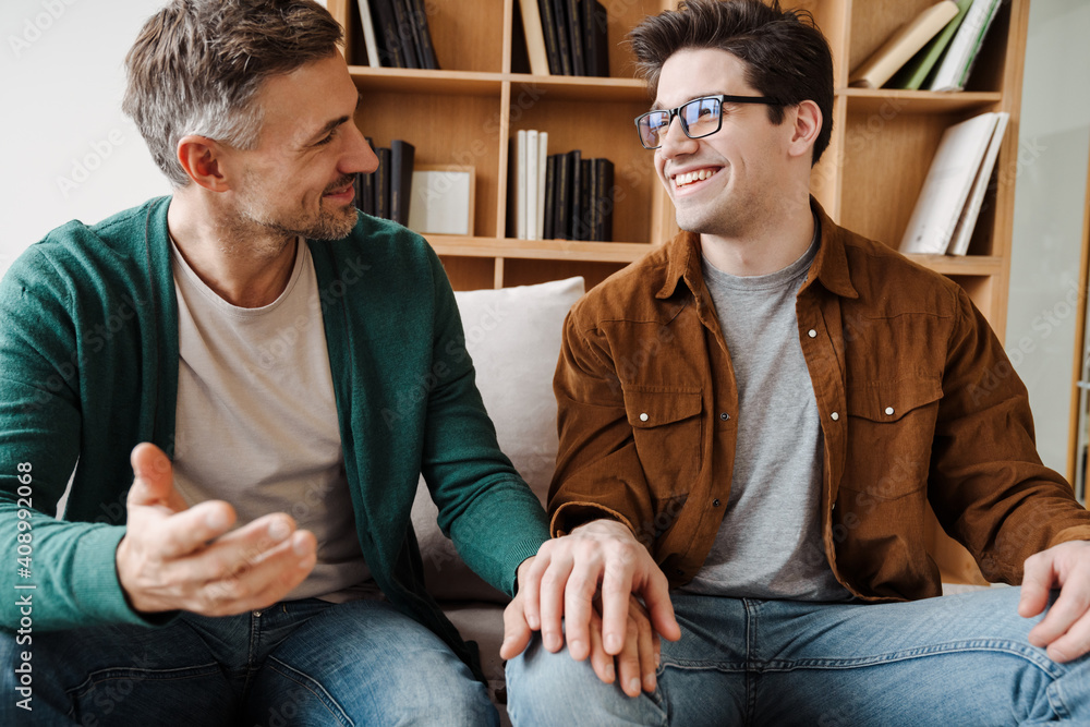 Wall mural happy young male gay couple talking while relaxing