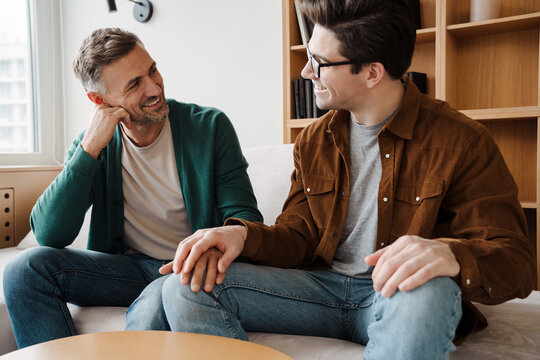 Happy young male gay couple talking while relaxing