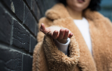 She extends her hand. Woman on street. Close up. Focus is on hand.