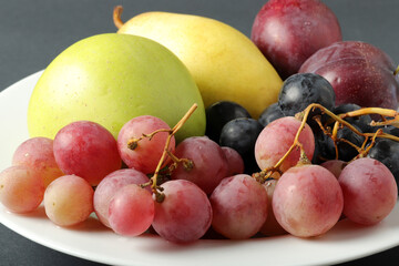 fresh fruits grape, plum, apple, pear in the plate
