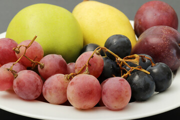 fresh fruits grape, plum, apple, pear in the plate