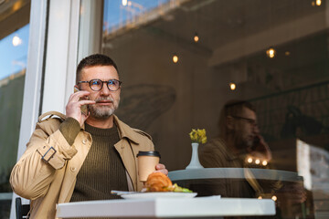 Businessman sitting at table in cafe using mobile phone