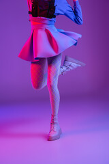 cropped view of stylish woman in skirt jumping on purple with pink lighting