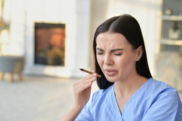 Disgusted young woman with cigarette at home. Concept of refusing from bad habit