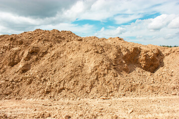 mountain with yellow sand, against a cloudy sky, on a summer day
