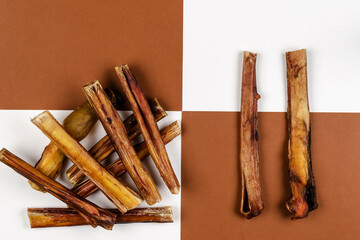 Dried bovine penis, bully sticks, beef pizzle for dogs on a brown and white background.