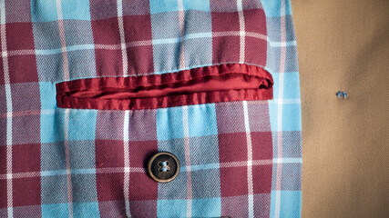 Bolsillo interior rojo con botón y forro de cuadros escoceses azul y rojo en gabardina camel