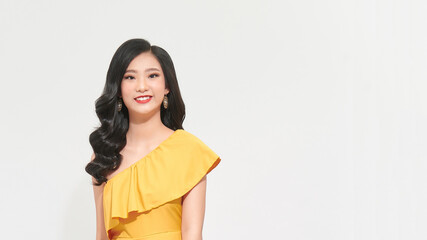 Positive young woman in yellow dress smiling at camera. Isolated over white background