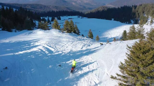 Snowbike riders in mountain valley in beautiful snow powder. Aerial video. Snowdirt bike with splashes and trail. Snowmobile winter sport riding
