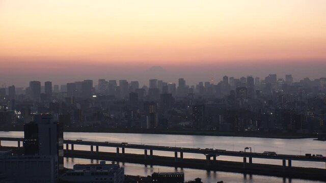 TOKYO, JAPAN : Aerial high angle sunrise CITYSCAPE of TOKYO and Mount Fuji. Buildings at central downtown area. Japanese urban metropolis concept. Wide time lapse zoom in shot night to morning.