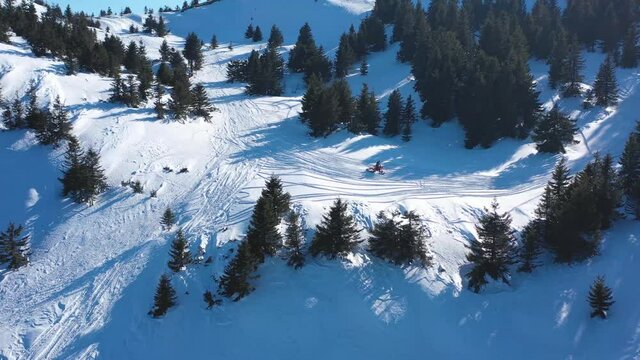 Snowbike riders in mountain valley in beautiful snow powder. Aerial video. Snowdirt bike with splashes and trail. Snowmobile winter sport riding