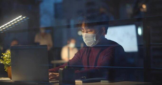 Portrait of contemporary asian man wearing mask in office while working late at night