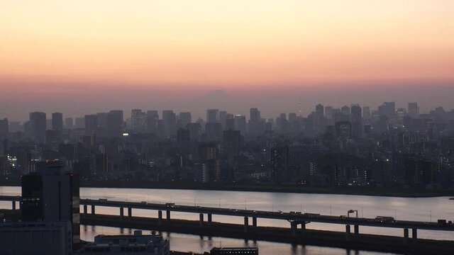 TOKYO, JAPAN : Aerial high angle sunrise CITYSCAPE of TOKYO and Mount Fuji. Buildings at central downtown area. Japanese urban metropolis concept. Wide time lapse zoom out shot night to morning.