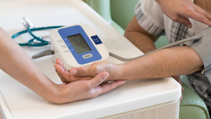 Caregiver checking old senior female people patient arterial blood pressure with digital arm sphygmomanometer gauge. Medical and Healthcare concept.