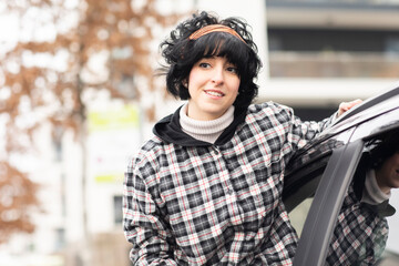 Junge Frau aussen mit Elektroauto, carsharingauto